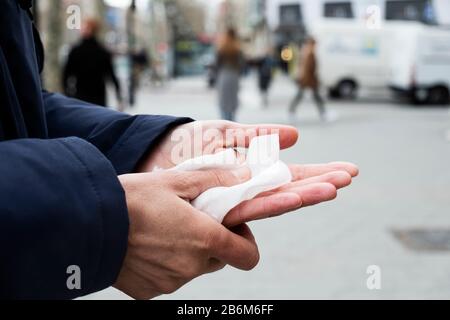 Nahaufnahme eines kaukasischen Mannes auf der Straße, der seine Hände mit einem feuchten Tuch desinfiziert Stockfoto