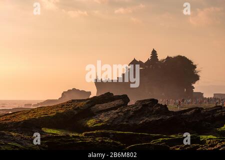 Uralter Tempel von Tanah Lot mit Touristen an der Küste bei Sonnenuntergang in Indonesien Stockfoto