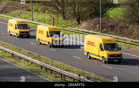 DHL International Shipping; Drei gelbe Transport-Lieferwagen, Lkw, Transport, Frachtführer, Deutsche Post DHL Vehicle, Commercial Transport, Industry, M6 in Manchester, Großbritannien Stockfoto