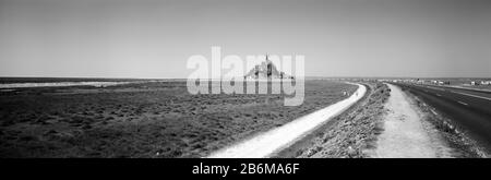 Straße, die durch eine Landschaft führt, der "Mont-Saint-Michel", Normandie, Frankreich Stockfoto