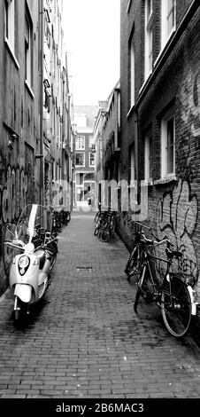 Roller und Fahrräder parkten in einer Straße, Amsterdam, Niederlande Stockfoto