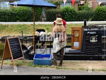 Blonde, haarige Frau, die Waren von einem vermoorten Schmalboot auf dem Llangollen-Kanal in Wales kauft. Stockfoto