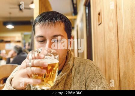 Ein junger Mann trinkt helles Bier in einer Bar oder Kneipe Stockfoto