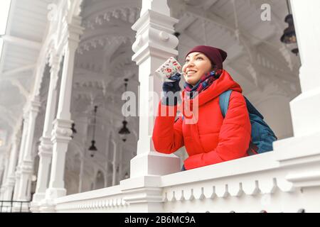 Junge Frau in der Jacke trinkt therapeutisches Mineralwasser aus einer Tasse eine natürliche heiße Quelle in Karlsbad zur Winterzeit, Tschechien Stockfoto