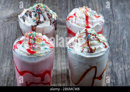 Vier Gläser bunte Milchshake-Cocktails - Chocolate Milchshake, Erdbeer-Milchshake, Caramel Milchshake, Milchshake mit frischen Beeren Stockfoto