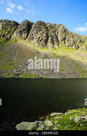 Goat's Water und Dow Crag in den Coniston Fells des englischen Lake District; Felskletterer sind nur erkennbar Stockfoto