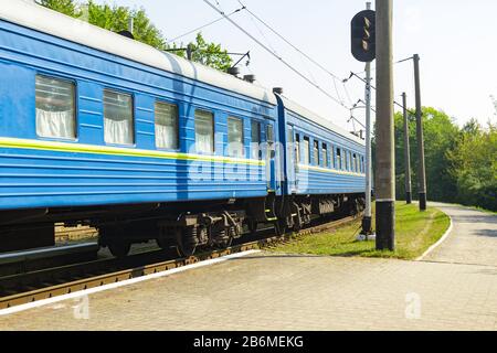 Der alte blaue Zug verlässt das Bahnhaus am Bahnhof. Stockfoto