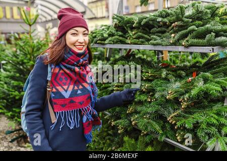 Mädchen wählt auf der Neujahrsmesse oder dem Markt einen Weihnachtsbaum Stockfoto