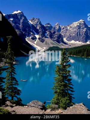 Blick auf das Kanu am Maligne Lake mit Wald und Bergen, die sich im Wasser, Banff National Park, Alberta, Kanada widerspiegeln Stockfoto