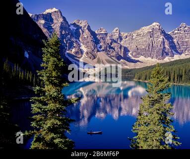 Blick auf das Kanu am Maligne Lake mit Wald und Bergen, die sich im Wasser, Banff National Park, Alberta, Kanada widerspiegeln Stockfoto