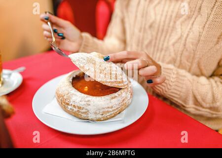 Frau, die im tschechischen Restaurant traditionelle Gulaschsuppe in Brot schmeckt Stockfoto