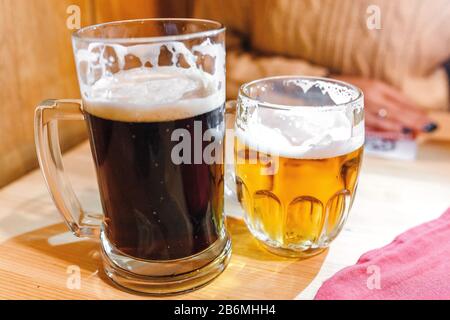 Zwei volle Bierbecher, dunkle und helle Lager mit Schaum in der tschechischen Bar Stockfoto