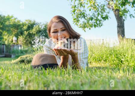 Frau Bauer hält zwei kleine neugeborene Babyhühner in den Händen Stockfoto