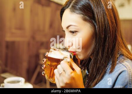 Schöne Brünette Ostfrau trinkt leichtes Handwerker-Bier in der Bar Stockfoto