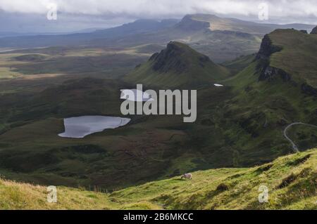 Lange kurvenreiche Straße bei Quiraing auf der Insel Skye mit einem wunderschönen, lebendigen schottischen Himmel. Stockfoto