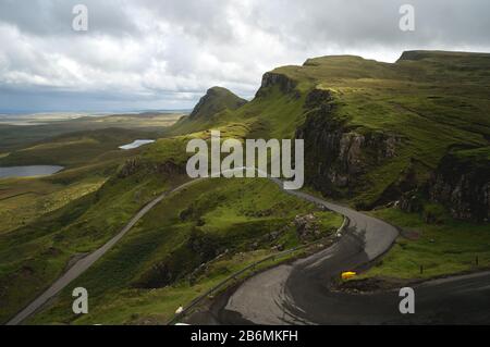 Lange kurvenreiche Straße bei Quiraing auf der Insel Skye mit einem wunderschönen, lebendigen schottischen Himmel.
