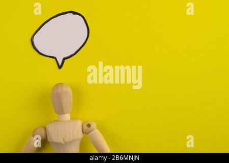 Handgefertigte Holzfigur Mannequin Modell Dummy-Puppe mit leerer Sprechblase auf orangefarbenem Hintergrund, Objekte, niemand Stockfoto