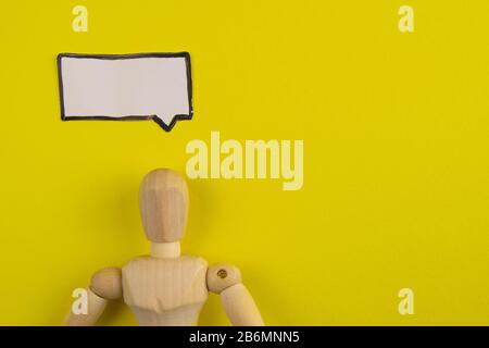 Handgefertigte Holzfigur Mannequin Modell Dummy-Puppe mit leerer Sprechblase auf orangefarbenem Hintergrund, Objekte, niemand Stockfoto