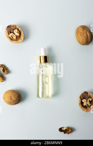 Kosmetik- und Heilöl aus Nussbaum auf blauem Pastellgrund. Nussbaum kosmetisches Feuchtigkeitsspendende Serum. Das Konzept der natürlichen Inhaltsstoffe in der Kosmetik. Stockfoto