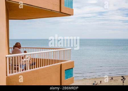 Mann auf Balkon Apartmentblock, Blick auf den Strand von Fuengirola, Andalusien, Spanien. Stockfoto