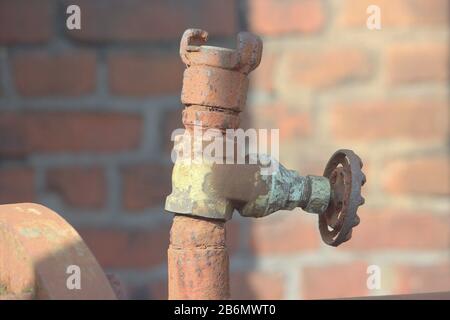 Verrostetes Eisenrohr mit Absperrventil in einer alten Fabrik Stockfoto