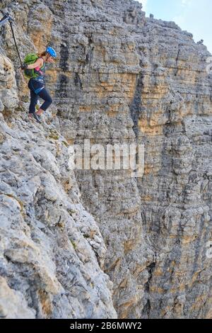 Mutiger weiblicher Kletterer, der von oben auf die Via ferrata Cesare Piazzetta, die Berge der Doles, Italien blickt. Sommer-Abenteuer-Tour mit beeindruckendem Stockfoto