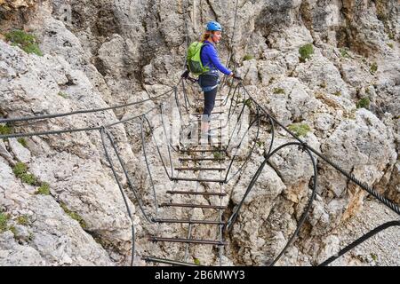 Frau auf einer via ferrata abgehängten Drahtbrücke an der Cesare Piazzetta klettersteig Route, Sellagruppe, Berge der Dolden, Italien. Stockfoto