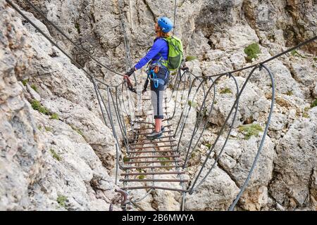 Frau auf der Via Ferrata Hängebrücke an der Cesare Piazzetta klettersteig Route, in den Bergen der Doles, Italien. Stockfoto