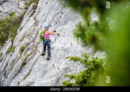 Frau Touristin auf einer Traverse am Intersport Klettersteig Donnerkogel über die Ferrata-Route, bei Gosau, in Österreich. Stockfoto