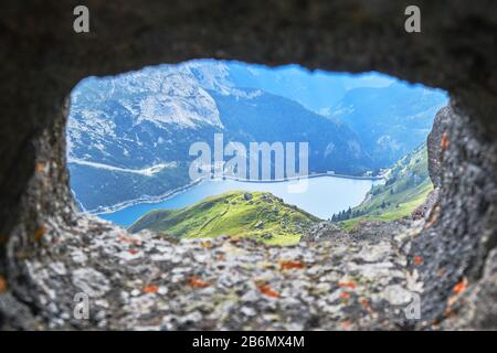 Fedaia See in den Bergen der Dolden, Italien, wie durch einen Felsriesel aus einem alten Kriegsstollen zu sehen. Stockfoto
