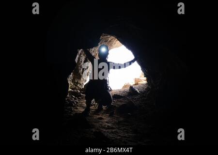 Historischer Tunnel im 1. Weltkrieg und eine Touristin mit Stirnlampe an der Via ferrata Delle Trincee (was bedeutet: Weg der Schützengräben) in Dolmit Stockfoto