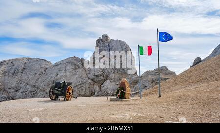 Marmolada, Italien - 28. August 2019: Gedenkstätte für den 1. Weltkrieg mit italienischen und europäischen Flaggen in der Nähe einer alten Kanone, am Punta Serauta, Marmolada-Gletscher. Stockfoto