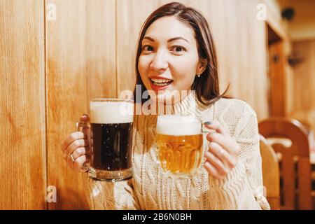 Junge asianerin mit zwei großen Bierkrügen an der Bar in der tschechischen Taverne Stockfoto