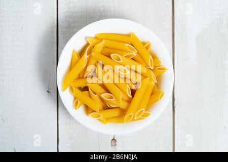 Schüssel mit roher Pasta auf Holztisch Stockfoto