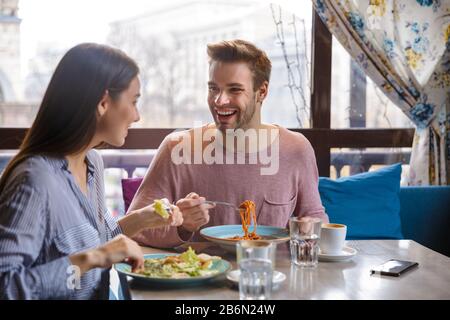 Attraktives junges Paar, das im Café zuhause zu Mittag essen und eine Mahlzeit zu sich nehmen kann Stockfoto