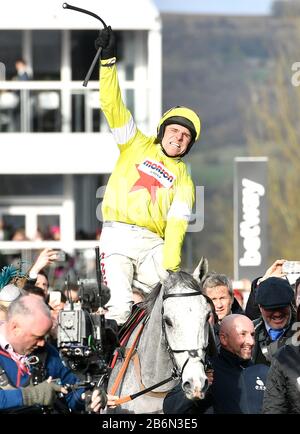 Politologe, der vom Jockey Harry Skelton geritten wird, feiert den Sieg im Betway Queen Mother Champion Chase am zweiten Tag des Cheltenham Festivals auf der Cheltenham Racecourse. Stockfoto