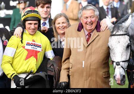 Jockey Harry Skelton (links), Besitzer John Hales und Horse Politologue, nachdem er am zweiten Tag des Cheltenham Festivals auf der Rennbahn von Cheltenham den Betway Queen Mother Champion Chase gewonnen hatte. Stockfoto