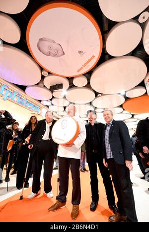 München, Deutschland. März 2020. Karen Webb (l-r), Moderatorin, Ottfried Fischer, Schauspieler, Alfons Schuhbeck, Starkoch, Barny Murphy und Günther Sigl, Musiker der Band Spider Murphy Gang, stehen in den Stachus-Passagen unter einem Deckenkreis im Sky of Fame mit einem Foto von Schubeck. Im Ruhmeshimmel, an den Deckenkreisen der Stachus-Passagen, befinden sich Bilder von Münchner Persönlichkeiten. Fischer, Schubeck, Murphy und Sigl enthüllten ihre Bilder am 11.03.2020. Credit: Tobias Hase / dpa / Alamy Live News Stockfoto