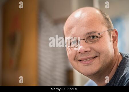 Nahaufnahme im Headshot-Porträt eines lächelnden 50-jährigen Mannes im Innenbereich. Stockfoto