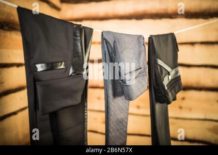 Dunkle, stylische Hosen und Jeans für Damen hängen an einem Seil in der garderobe. Das Konzept, Kleidung für jeden Tag zu wählen. Elegantes Damenbekleidungskonzept Stockfoto