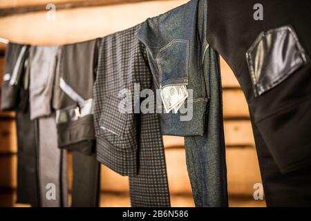 Dunkle, stylische Hosen und Jeans für Damen hängen an einem Seil in der garderobe. Das Konzept, Kleidung für jeden Tag zu wählen. Elegantes Damenbekleidungskonzept Stockfoto