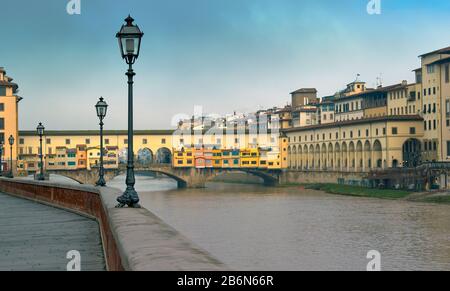 FLORENZ ITALIEN DIE MEHRFARBIGE BRÜCKE PONTE VECCHIO ÜBER DEN FLUSS ARNO UND AM UFER Stockfoto