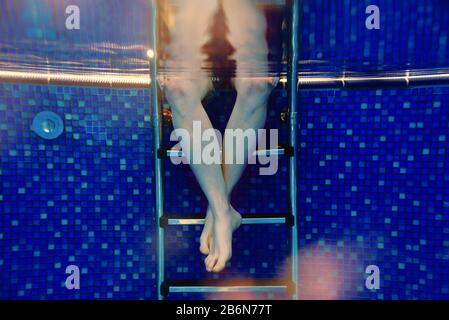 Männer Beine auf der Treppe unter Wasser im Schwimmbad im Sommer Stockfoto