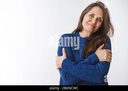 Granny Waits Familie kommen sehen Sie sie in den Ferien umarmend sich eng, Tiltign Kopf an der Schulter und lächelnd niedlich, mit blau-warmem Pullover, Gefühl Stockfoto