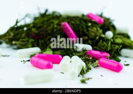 Makrofoto von einem großen Knospenstapel und Marihuanablättern mit mehrfarbigen Pillen in großen Mengen. Das Konzept, Opioide durch Cannabis zu ersetzen Stockfoto