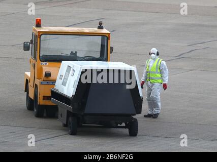 Eine Person, die Schutzkleidung und eine Gesichtsmaske trägt, auf der Rollbahnschürze als Flugzeug, das Passagiere aus dem Coronavirus befördert, trifft Grand Princess auf dem Flughafen Birmingham, nachdem sie aus den USA zurückgeführt wurden. Stockfoto