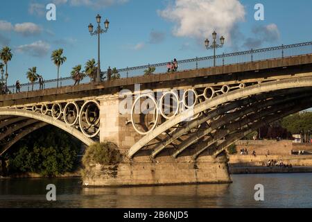 Seitlicher Blick auf die Triana-Brücke, die älteste Brücke von Sevilla, über den Fluss Guadalquivir, fotografiert vom Wasser, Sevilla, Spanien Stockfoto