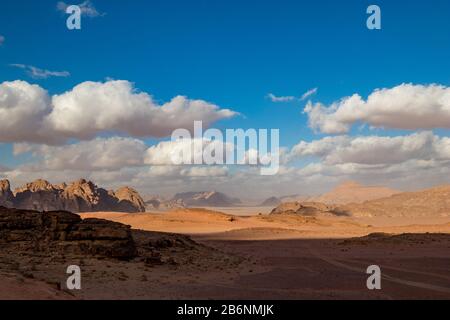 Königreich Jordanien, Wüste Wadi Rum, sonnige Landschaft am Wintertag mit weißen, pfiffigen Wolken und warmen Farben. Schöne Reisefotografie. Schöne Wüste konnte auf Safari erkundet werden Stockfoto