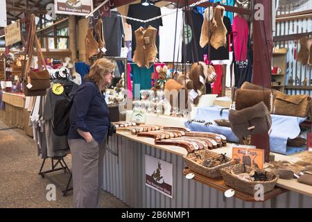 dh Kuranda Village CAIRNS AUSTRALIEN Frau Tourist Rain Forest Heritage Market Kangaroo Skins stall Interieur Stockfoto
