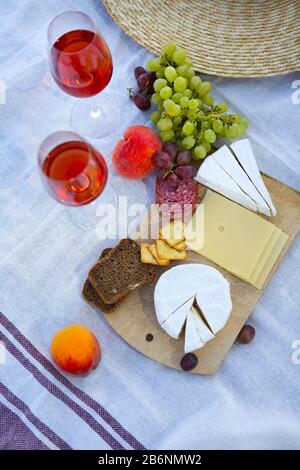 Am Sommerabend können Sie ein romantisches Picknick mit einer Brille Wein mit Obst und Käse auf der Decke an der felsigen Küste machen Stockfoto